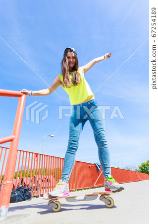 Teen girl skater riding skateboard on street. 67254189