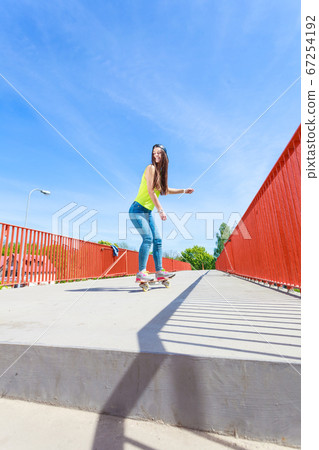 Teen girl skater riding skateboard on street. 67254192