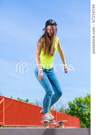 Teen girl skater riding skateboard on street. 67254194
