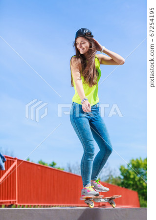 Teen girl skater riding skateboard on street. 67254195