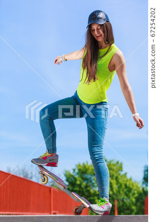 Teen girl skater riding skateboard on street. Teen girl skater riding skateboard on street. 67254202