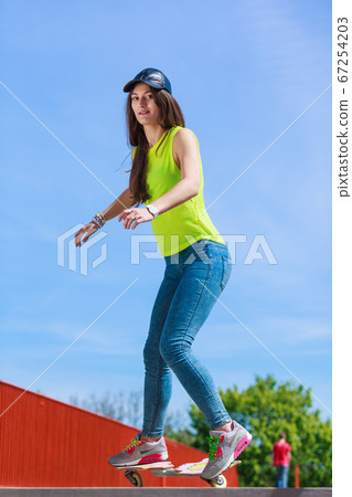 Teen girl skater riding skateboard on street. 67254203