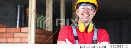 Happy builder stands near brickwork and smiles Happy builder stands near brickwork and smiles 67254342