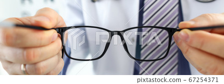 Male medicine doctor hands giving pair of black glasses 67254371