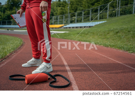 young cheerful personal fitness trainer at running track and with tablet young cheerful personal fitness trainer at running track and with tablet 67254561