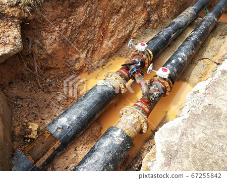 KUALA LUMPUR, MALAYSIA -JUNE 02, 2017: Underground utility and services pipe laid by workers in the trenches at the construction site. Installation of stop cork valve and joint in progress. KUALA LUMPUR, MALAYSIA -JUNE 02, 2017: Underground utility and services pipe laid by workers in the trenches at the construction site. Installation of stop cork valve and joint in progress. 67255842