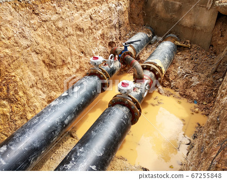 KUALA LUMPUR, MALAYSIA -JUNE 02, 2017: Underground utility and services pipe laid by workers in the trenches at the construction site. Installation of stop cork valve and joint in progress. KUALA LUMPUR, MALAYSIA -JUNE 02, 2017: Underground utility and services pipe laid by workers in the trenches at the construction site. Installation of stop cork valve and joint in progress. 67255848