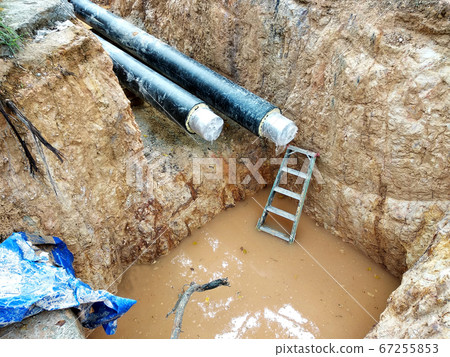 KUALA LUMPUR, MALAYSIA -JUNE 02, 2017: Underground utility and services pipe laid by workers in the trenches at the construction site. Installation of stop cork valve and joint in progress.    67255853