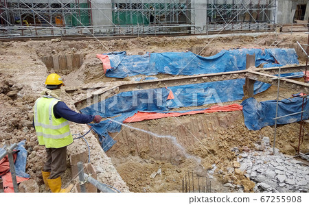 KUALA LUMPUR, MALAYSIA -JUNE 29, 2017: Construction workers spraying the anti termite chemical treatment to the soil at the construction site. KUALA LUMPUR, MALAYSIA -JUNE 29, 2017: Construction workers spraying the anti termite chemical treatment to the soil at the construction site. 67255908