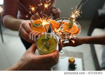 Goup of people holding cocktails in their hands with sparklers Goup of people holding cocktails in their hands with sparklers 67256363