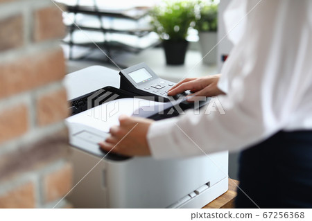 Woman in office prints documents on printer 67256368