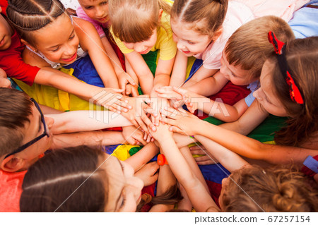 Children holding hands together, laying on a floor Children holding hands together, laying on a floor 67257154