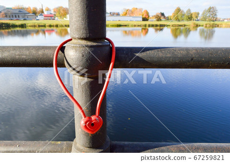 A red barn lock in the shape of a heart hangs 67259821