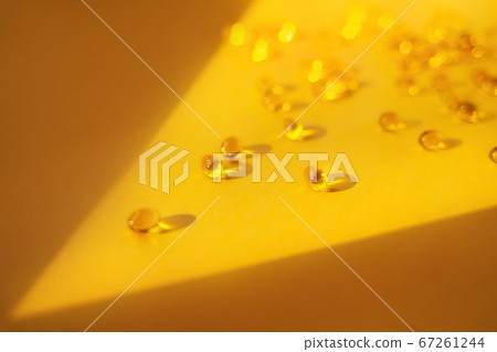 Gelatin capsules in a ray of light on a yellow background. Dietary supplement, health care, soft focus 67261244