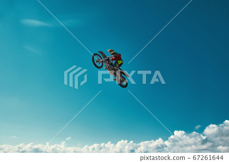 Extreme concept, challenge yourself. Extreme jump on a motorcycle on a background of blue sky with clouds. Copy space, all or nothing. Extreme concept, challenge yourself. Extreme jump on a motorcycle on a background of blue sky with clouds. Copy space, all or nothing. 67261644