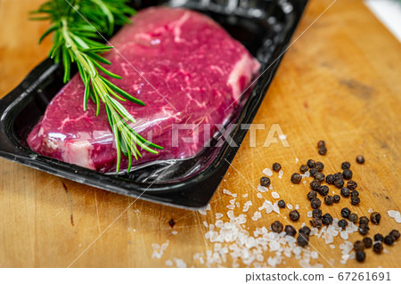 Beef steak in vacuum skin packaging and spices on wooden chopping board 67261691