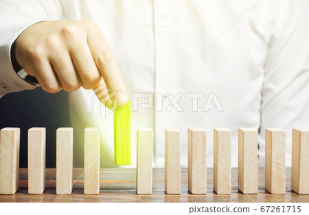 A man puts green dominoes in a row. Business management and processes. Correct errors, make improvements. Risk management, integration into upgrades to the system, implementation into legislation. A man puts green dominoes in a row. Business management and processes. Correct errors, make improvements. Risk management, integration into upgrades to the system, implementation into legislation. 67261715
