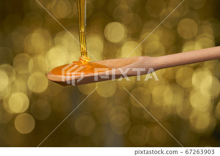 organic honey flows on a wooden dipper, close up. 67263903
