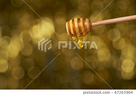Honey dripping from honey dipper on yellow Honey dripping from honey dipper on yellow 67263904