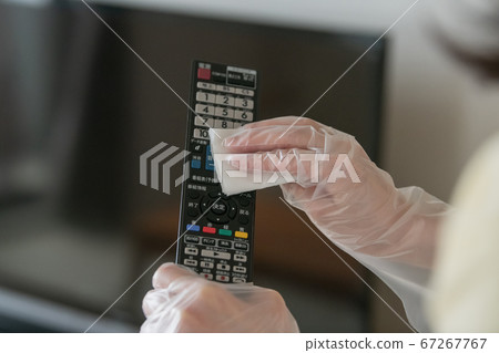 用消毒片擦拭電視機的遙控器一名戴著乙烯基手套的女人的手 67267767