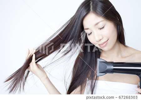 婦女用吹風機烘乾她的頭髮。 67268303