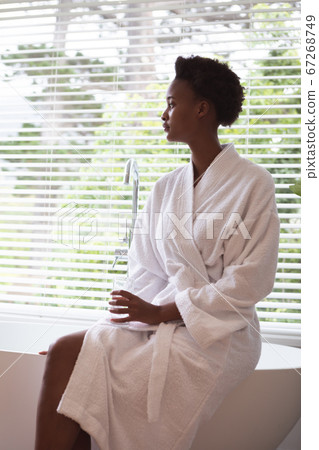 Woman with glass sitting on bathtub Woman with glass sitting on bathtub 67268749