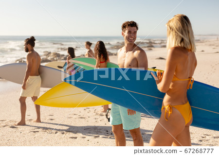 Mixed race people holding surf board on beach Mixed race people holding surf board on beach 67268777