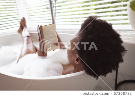 Woman reading book in a bathtub Woman reading book in a bathtub 67268782