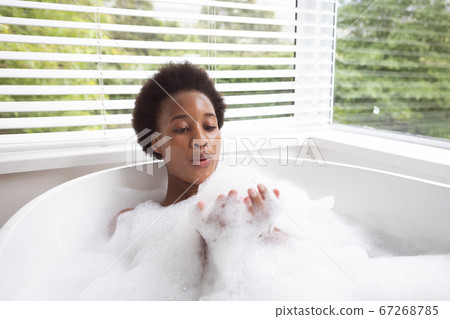 Woman blowing bubbles in a bathtub 67268785