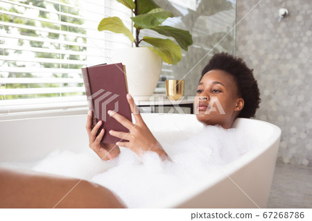 Woman reading book in a bathtub 67268786