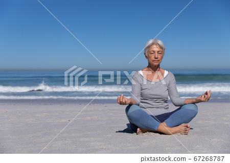 Senior Caucasian woman meditating at the beach. Senior Caucasian woman meditating at the beach. 67268787