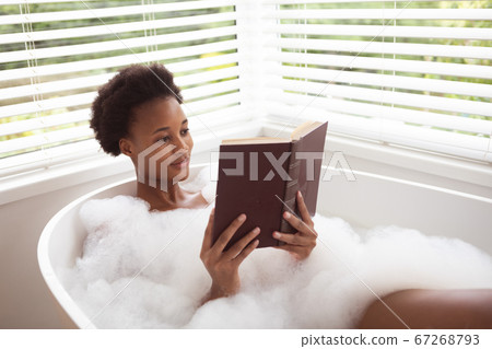 Woman reading book in a bathtub Woman reading book in a bathtub 67268793