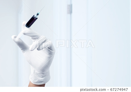 Doctor man in protective gloves holding a syringe Doctor man in protective gloves holding a syringe 67274947