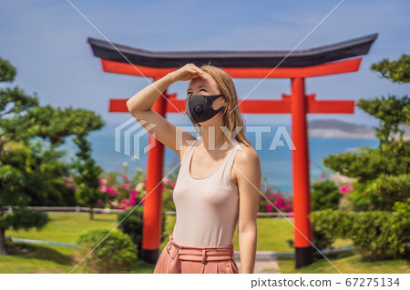 traveler in medical mask stopped on the street and looking at the Japanese traditional building. Tourists travel in Japan after the coronavirus epidemic traveler in medical mask stopped on the street and looking at the Japanese traditional building. Tourists travel in Japan after the coronavirus epidemic 67275134