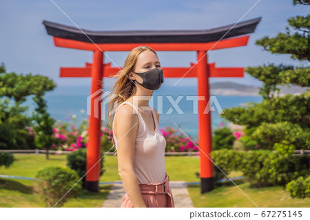 traveler in medical mask stopped on the street and looking at the Japanese traditional building. Tourists travel in Japan after the coronavirus epidemic traveler in medical mask stopped on the street and looking at the Japanese traditional building. Tourists travel in Japan after the coronavirus epidemic 67275145