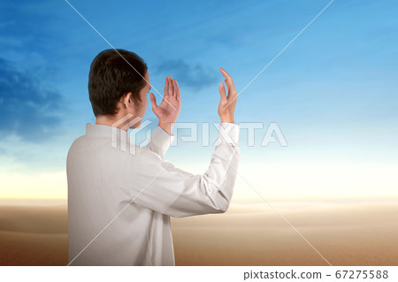 Rear view of Asian Muslim man standing while Rear view of Asian Muslim man standing while 67275588