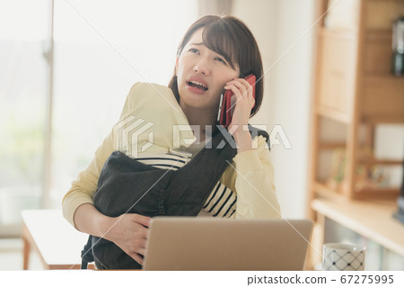 Image of a Japanese woman who takes care of her baby at home and performs telework, remote work, and homework 67275995