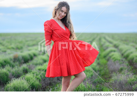 Happy woman in red dress dancing and jumping in lavender field 67275999