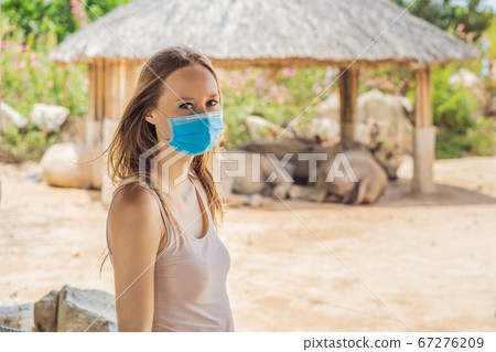 Young woman at the zoo in a medical mask. Visiting public places after the coronavirus epidemic 67276209