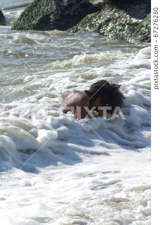 Solitary young boy laughs while playing in the ocean waves. Solitary young boy laughs while playing in the ocean waves. 67276280
