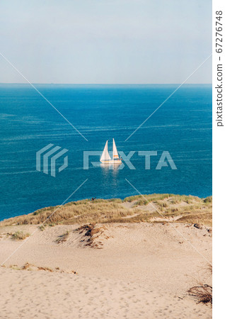 White Sailboat On the background of Dunes and Blue Sky in the sea.White sailboat in the Baltic sea.Lithuania.Nida 67276748
