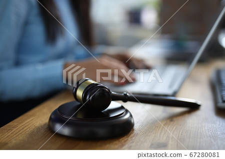Woman sits on table next to her lies wooden gavel for court hearings Woman sits on table next to her lies wooden gavel for court hearings 67280081