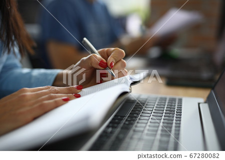 Woman in office sits at desk and makes notes in notebook. business Woman in office sits at desk and makes notes in notebook. business 67280082
