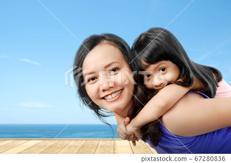 Asian mother carrying her little girl on her back 67280836