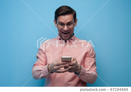 Portrait of a handsome young man in glasses with smartphone Portrait of a handsome young man in glasses with smartphone 67284889