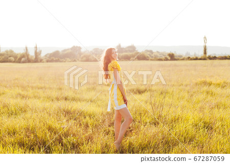 portrait of a beautiful woman in a yellow dress in a field at sunset 67287059