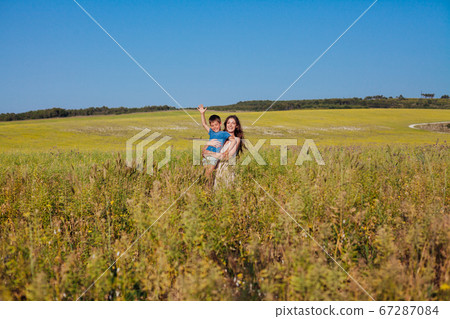Portrait of a beautiful mom and son on a walk on nature field road Portrait of a beautiful mom and son on a walk on nature field road 67287084