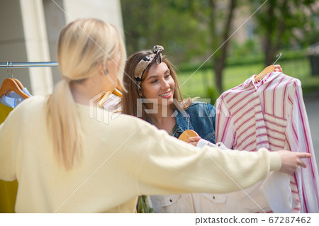 Nice young women discussing which clothes to buy Nice young women discussing which clothes to buy 67287462