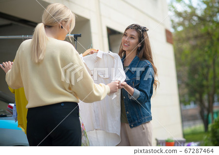 Positive nice woman offering the blouse to the customer Positive nice woman offering the blouse to the customer 67287464