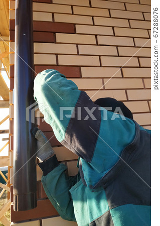 The worker attaches to the wall of the house drainage. The worker attaches to the wall of the house drainage. 67288076